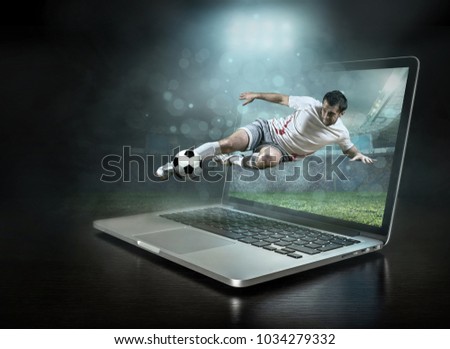 Caucassian soccer Player in dynamic action with ball in a professional sport game play on the laptop in football under stadium lights.