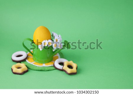 Easter decoration with egg and watering can on a green background.