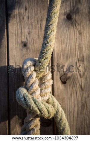 Reliable and secure sea knot.Security concept.Tied water craft ropes in close up.Motor boat anchor tied in haven with old rope