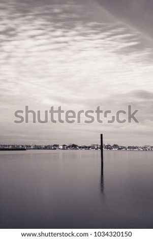 seascape view in long exposure in black and white on atlantic coastline with boat pole isolated, basque country, france