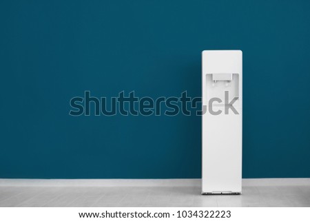 Modern water cooler near color wall