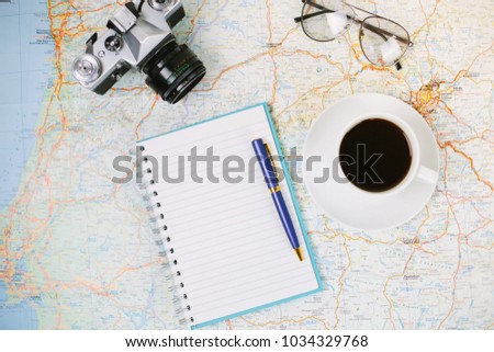 Planning time travel with cup of coffee on map, with photo camera, sunglasses, notebook and pen.