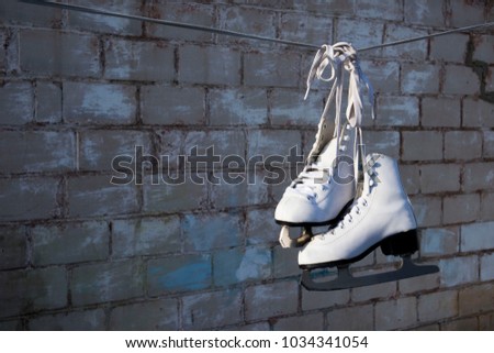 white skates hanging on a rope against a brick wall
