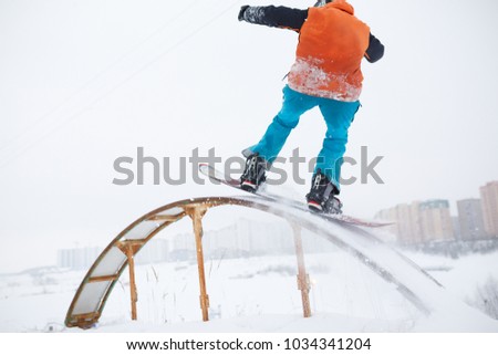 Photo from back of athlete skating on snowboard with springboard