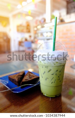Blurred picture of green tea latte and brownies in coffee shop with space for your text and design. Concept be used for recommended menu in coffee shop and business of bakery shop.
