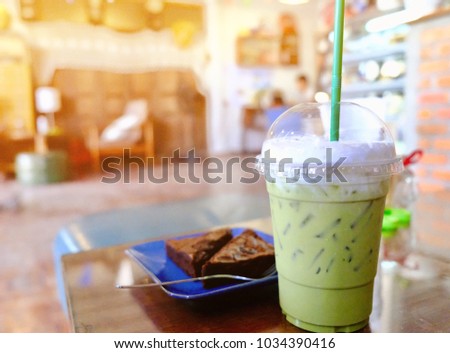 Blurred picture of green tea latte and brownies in coffee shop with space for your text and design. Concept be used for recommended menu in coffee shop and business of bakery shop.