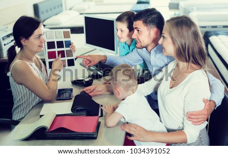 Positive spanish saleswoman in furniture store helping young family in choice of mattress material