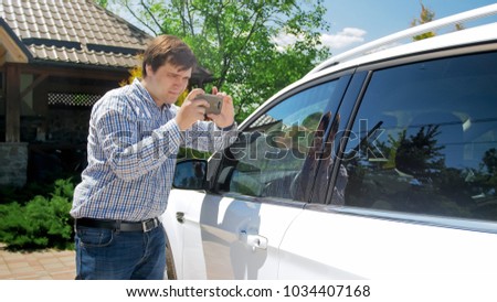 Man making photos on smartphone of his car