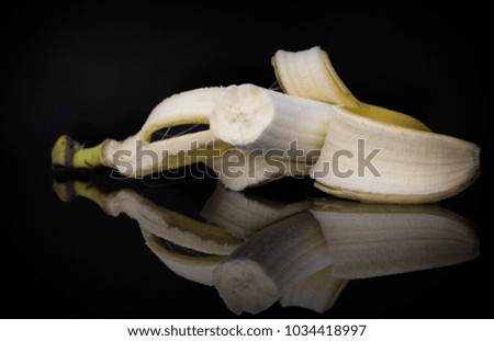 Fresh peeled banana on black background with the reflection. Macro photo