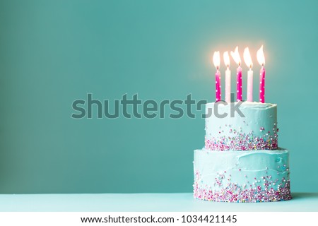 Tiered birthday cake with pink candles and sprinkles