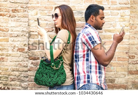 Bored multiracial couple using mobile smart phone - Addiction isolation concept with millennials young people using smartphone - Boyfriend and girlfriend on disinterest moment - Warm neutral filter