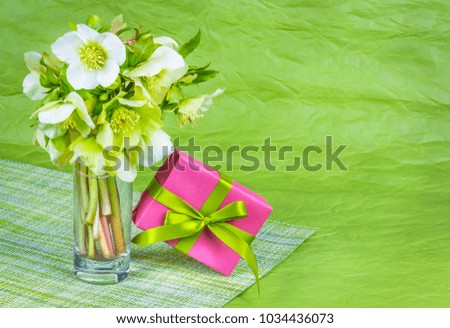 Bouquet of spring flowers and box with gift on green background. Bouquet of hellebells. International Women's Day. Romantic concept.