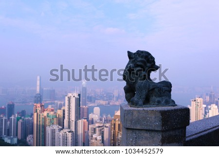 Asian sculpture in front of the view from Victoria Peak in Hong Kong