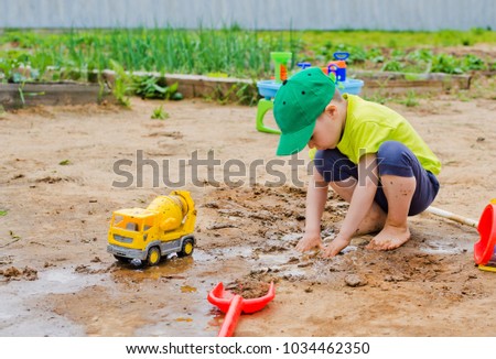 the child plays in the summer in the mud