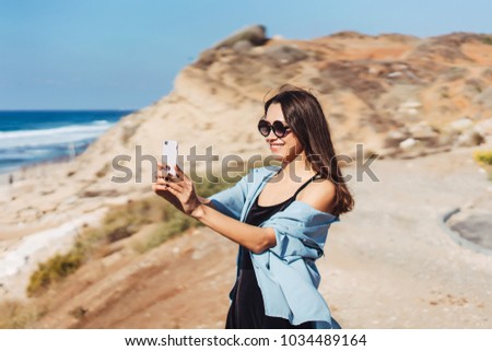 Young woman take a photo on smartphone on the beach