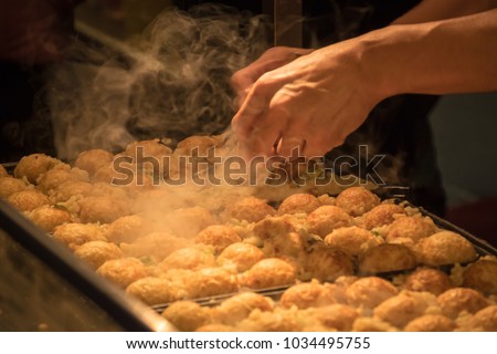 Japanese cook has made Takoyaki for tourist. Takoyaki is a ball-shaped Japanese snack made of a wheat flour-based batter and cooked in a special molded pan
