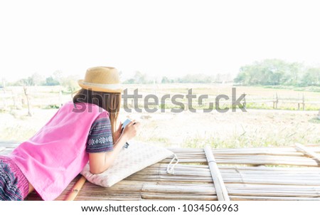 The women wearing a hat is holding a camera down on the wood while on vacation in the countryside,quiet.