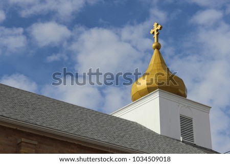 Ornate country church with gold gilded dome steeple against bright blue skies