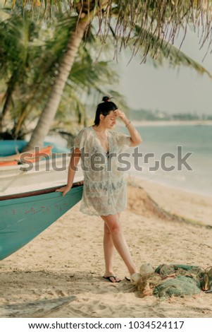 the girl holds onto the boat near the ocean under the palm trees
