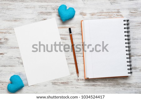 Hearts and blank notepad with pencil on wooden table