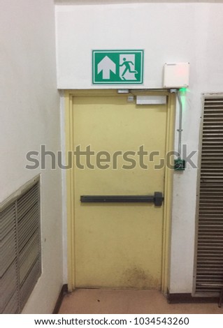 Door to exit, fire exit. A door is yellow. It's automatic close door. There is fire exit sign above the door.