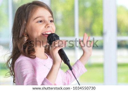 Beautiful little girl with microphone  Royalty-Free Stock Photo #1034550730