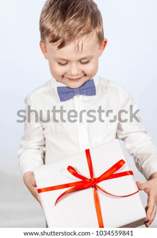 Cute little boy with a gift. Happy boy holding a box with a gift. Mothers Day. International Women's Day. Portrait of a happy little boy on a white background. Spring. Birthday. Cozy.