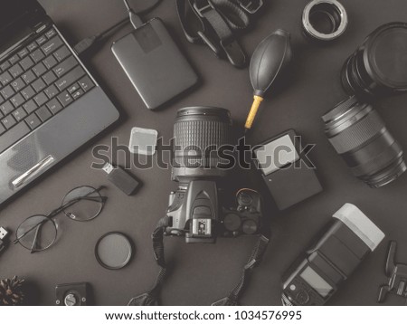 top view of work space photographer with digital camera, flash, cleaning kit, memory card, external harddisk, USB card reader and camera accessory on black table background