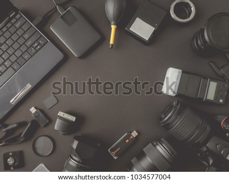 top view of work space photographer with digital camera, flash, cleaning kit, memory card, external harddisk, USB card reader and camera accessory on black table background with copyspace.