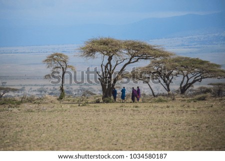 African savanna landscape with acacia trees and Masai tribal people at Ngorongoro National Park, Tanzania
