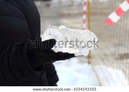 A piece of a large icicle in the palm of a woman. Fall from the roof. Danger to life.