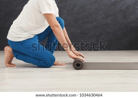 Unrecognizable man rolling up yoga mat after training. Sport class before or after practicing yoga, preparing for exercise, side view, copy space