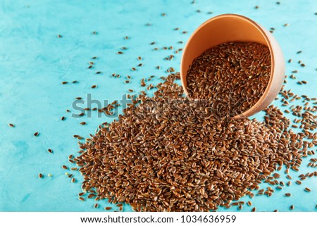 Close-up picture of flax seeds in a clay bowl isolated on blue background.