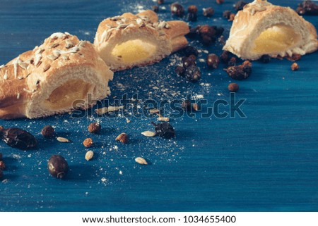 Three pieces of baked pie with custard stuff laying on a blue wooden background between dried berries, with a text space provided at a upper left corner and lower right corner. Warm colours