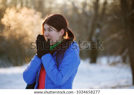 Photo of sporty woman warming her hands in winter forest