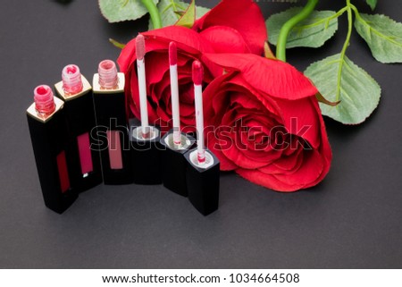 Flowers rose,Powder and Liquid lipstick brush uses lips for women,Beauty cosmetic black background. Makeup essentials item isolated on black background