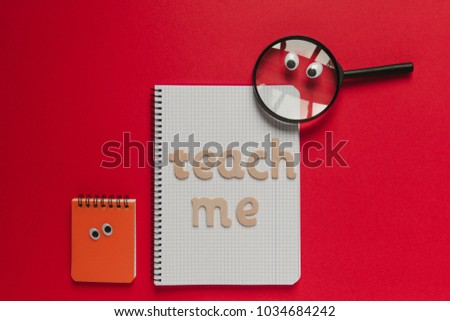 Wooden "Teach me" lettering on a school class and magnifying glass with eyes