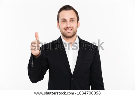 Portrait of happy entrepreneur wearing black formal suit and showing thumb up on camera with smile isolated over white background