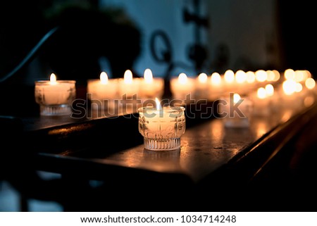 Lighted candles in the Church on the table on the background of cross reflection, religious tradition, prayer