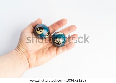 Two blue chinese yin yang balls in hand on white background. Nice details of beautiful baoding health balls. Great alternative medicine against stress. 
