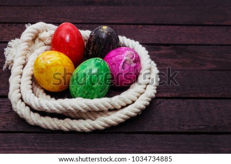Painted Easter egg in rope on wood background