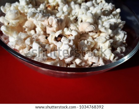 Popcorn in a transparent bowl on a red background