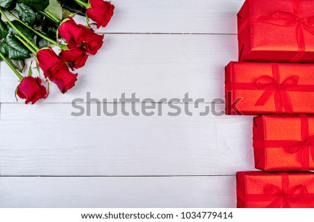 Bouquet of red roses and gift boxes on white wooden background, copy space. Greeting card mockup for Saint Valentines Day, Womens Day (March 8), Mothers Day. Top view, flat lay. Love concept