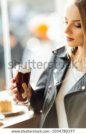 Pretty girl hold a cup of delicious coffee and waer glasses. Sun shine photo with girl drink her cappucino