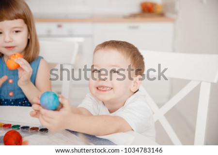 Childhood in Christian family, Children girl and boy with mother paint eggs and show them in camera.