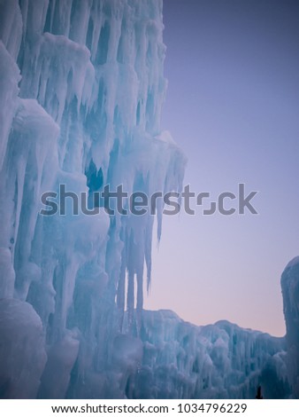 Winter ice cave with frozen icicles at sunset.
