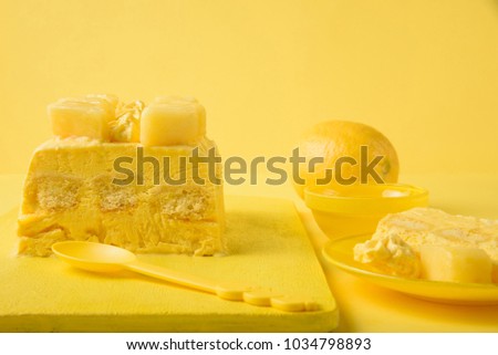 Semifreddo with lemon, savoiardi and saffron, decorated with meringue, pineapple and honey on a yellow background in monochrome