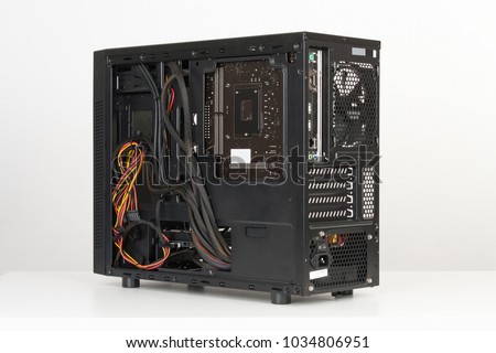 Building of PC, black computer case, midi tower for micro ATX motherboard on white table, back view without side panel