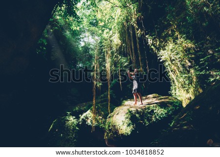 Male tourist walking in joungles and making photos during excited trip in asia wood forest.Experienced traveller taking pictures exploring green vegetation and wild nature of tropical trees