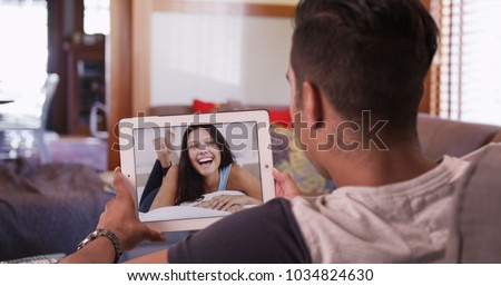 Cute millennial couple video chatting or having a facetime conversation with his girlfriend on tablet computer Royalty-Free Stock Photo #1034824630